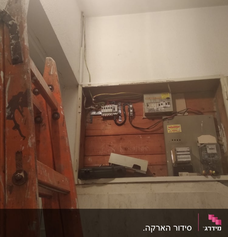 ארון חשמל פתוח עם חוטים וסולם כתום